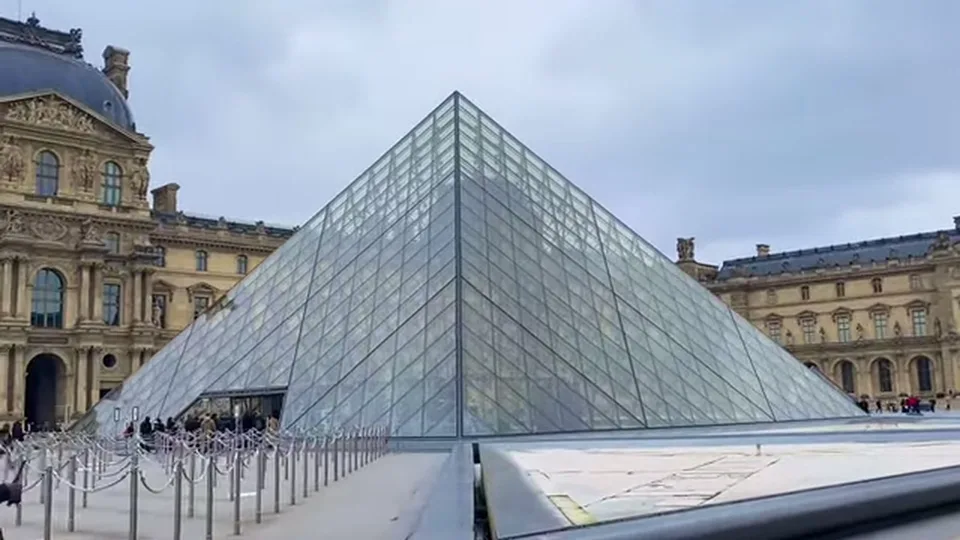 Glass pyramid at the Louvre courtyard framed by historic palace wings