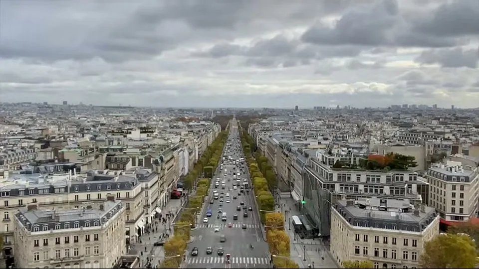Front view of the Arc de Triomphe from the road with cars and scooters in Paris