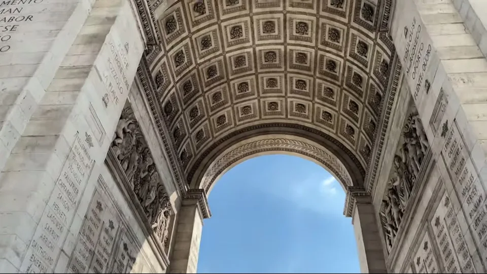 Tomb of the Unknown Soldier beneath the Arc de Triomphe with flowers and boulevard beyond