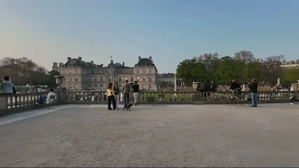 Seated visitors and a marble statue on the terrace at Luxembourg Gardens